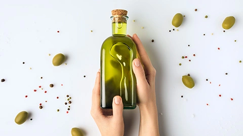 Frau hält Flasche mit Olivenöl in der Hand
