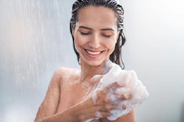 Frau wäscht ihren Körper unter der Dusche mit Duschschaum