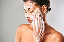 Frau säubert ihr Gesicht mit Reinigungsschaum
