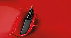 Lippenstift fällt in rote Flüssigkeit